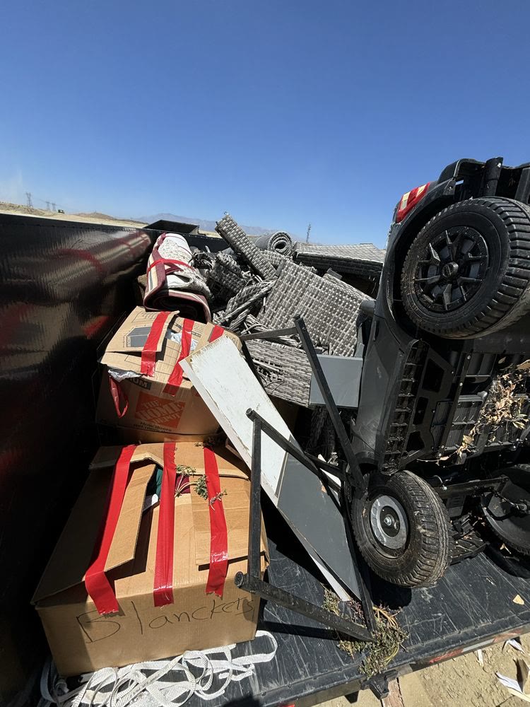 Loaded trailer with patio furniture, boxes and an ATV hauled to the landfill