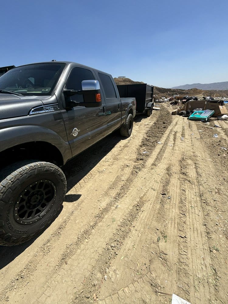 JC's Junk Removal truck towing a loaded dump trailer at the landfill