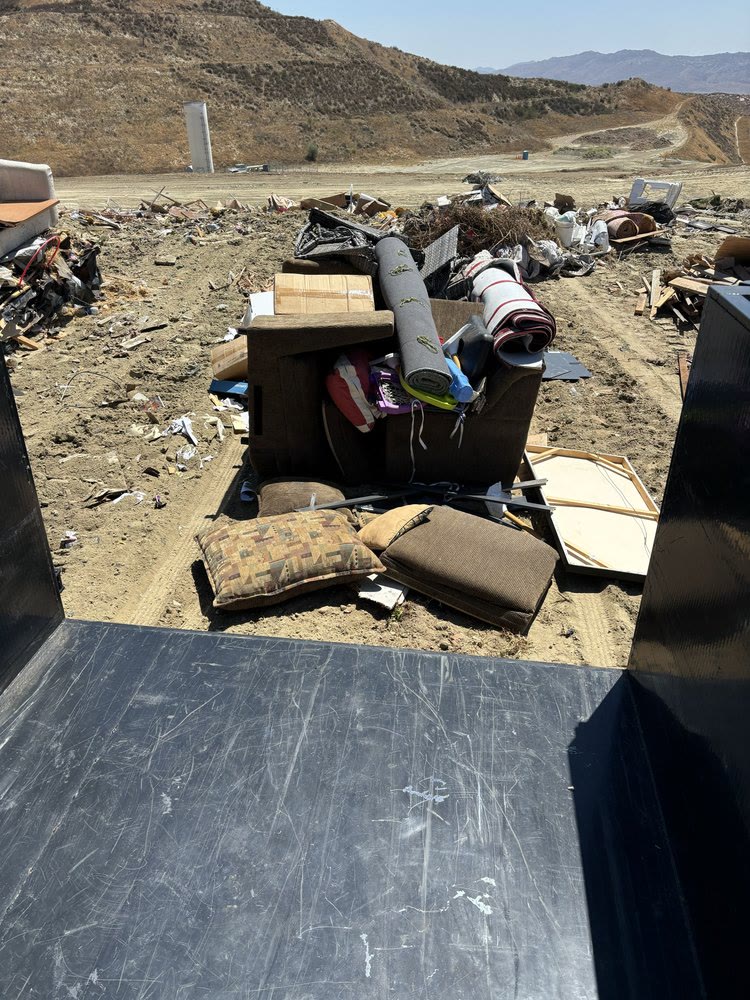 Trailer unloading a couch, rugs and household items at the disposal site